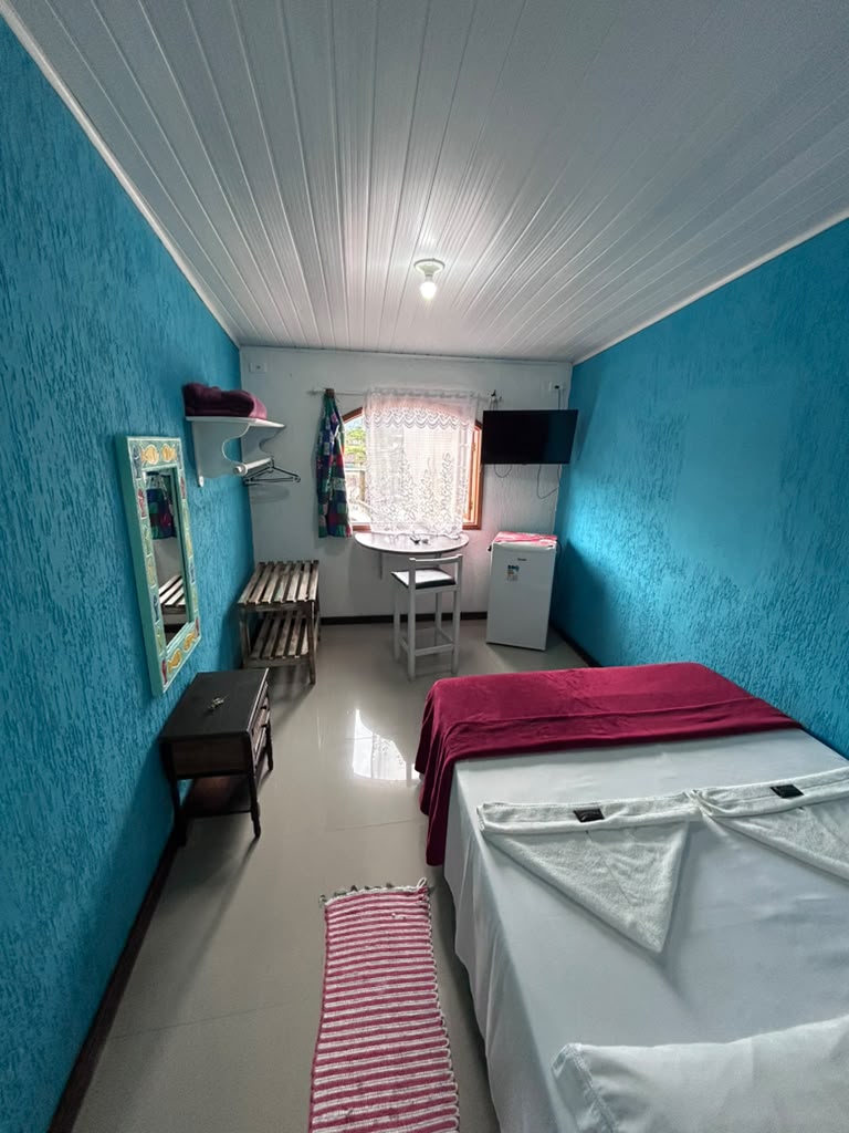 Quarto standard verde-água com frigobar e mesa